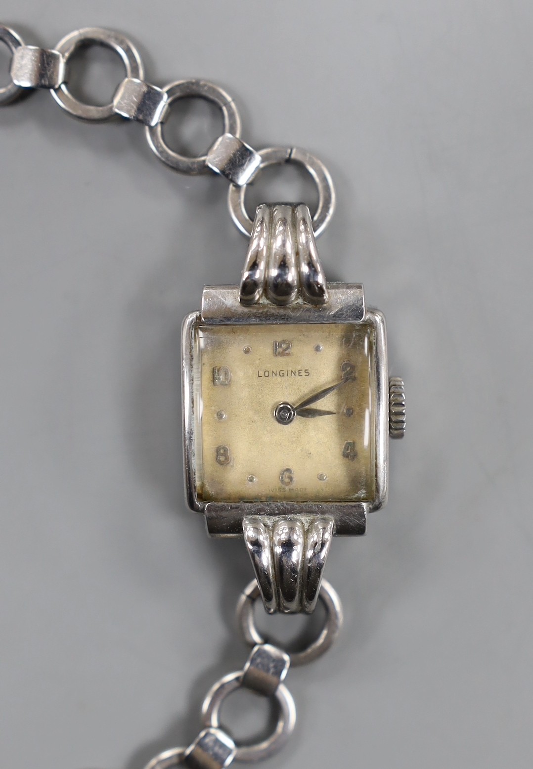 A lady's stainless steel Longines manual wind wrist watch, with fluted lugs, on associated steel chain link bracelet.